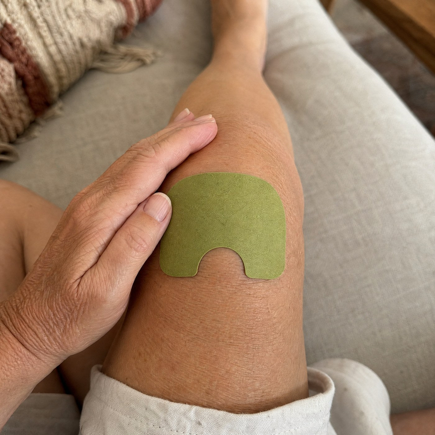 Patch chauffant Flevio appliqué sur un genou, main lissant le patch